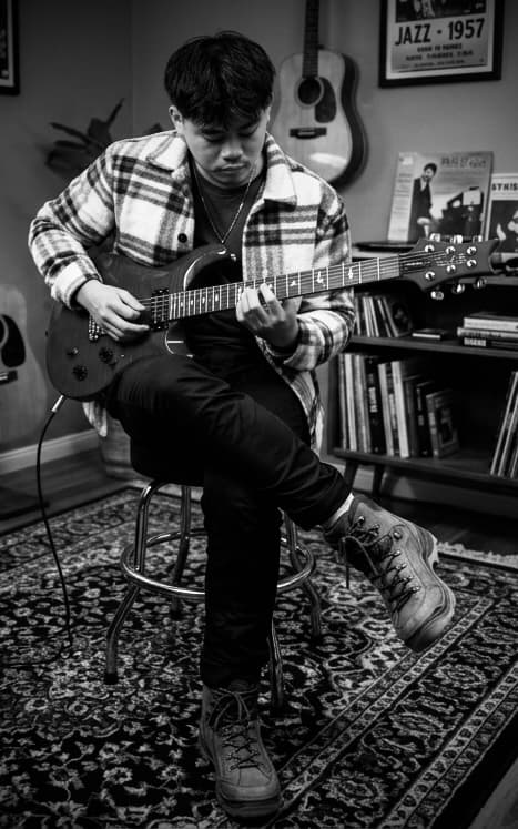 Jin, guitar instructor, seated with an electric guitar